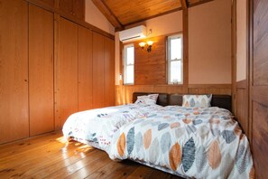 A bedroom with a wooden floor, a bed with a leaf-patterned bedspread, two windows with wall-mounted lights, and a wooden ceiling. - 5LDK with natural hot spring and the ocean view - Gift Villa / Beppu Ōita (Beppu)