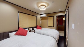 A hotel room with two beds, a ceiling light, an air conditioning unit, and a door leading to another room.