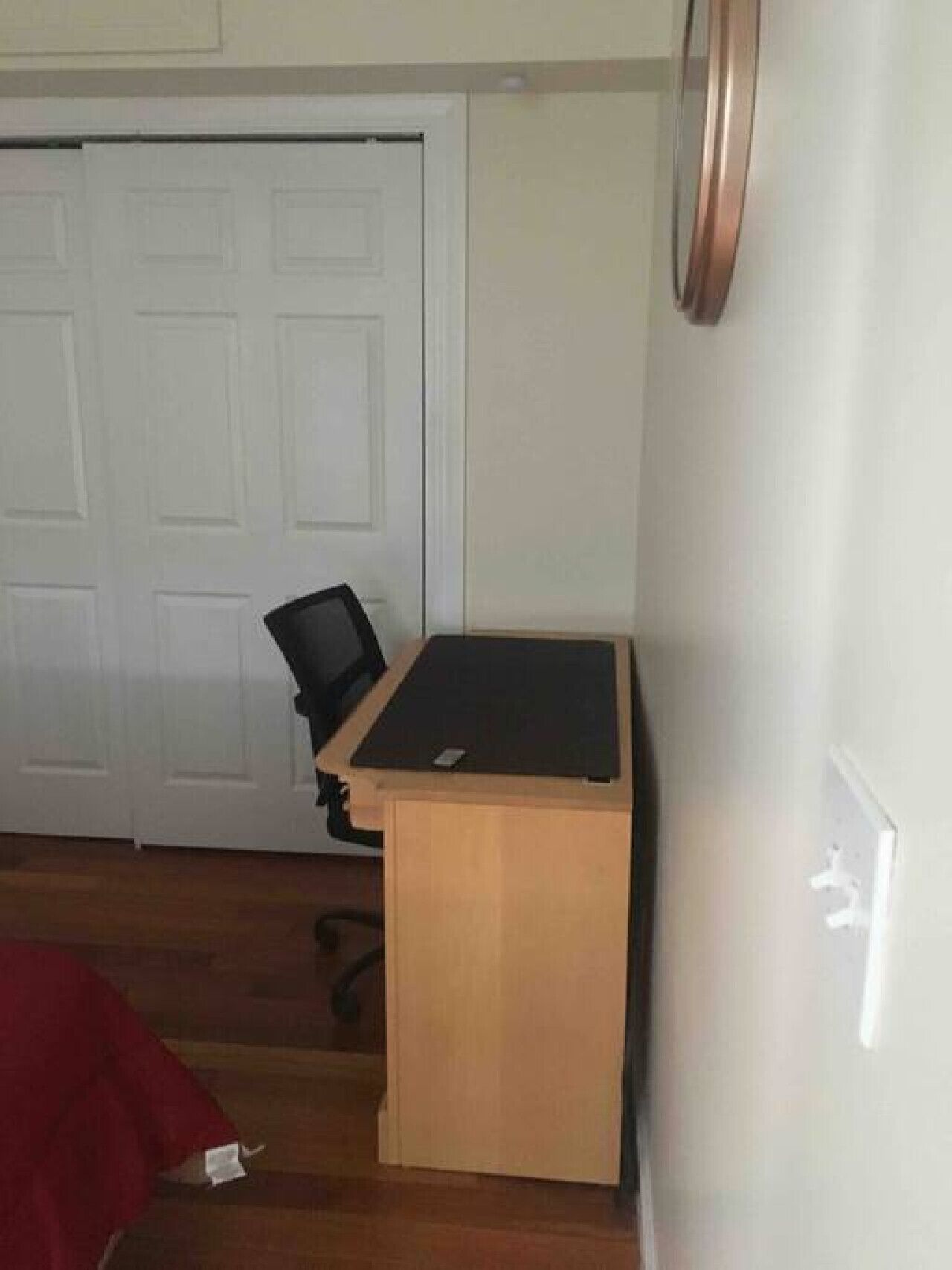 Ein Zimmer mit einem Holztisch, einem Stuhl und einer geschlossenen Tür.