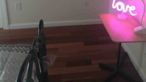 Una habitación con suelo de madera, un escritorio con un letrero de neón que dice 'love' y un cuadro en la pared.