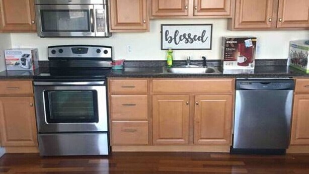 Una cocina con armarios de madera, electrodomésticos de acero inoxidable y un cartel que dice 'bendecido'.