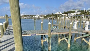 En træbro, der strækker sig ud i klart, blåt vand, med et skilt der siger "Tahiti Time".