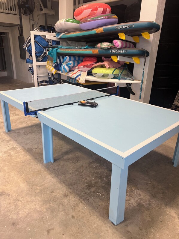 A ping pong table with a blue table and net, surrounded by a white shelf with various colorful items. - 7BR7BA, Pool, 2 Boat slips, steps to Tahiti Beach, Sleeps 18, +cabana adds 2 (Elbow Cay)