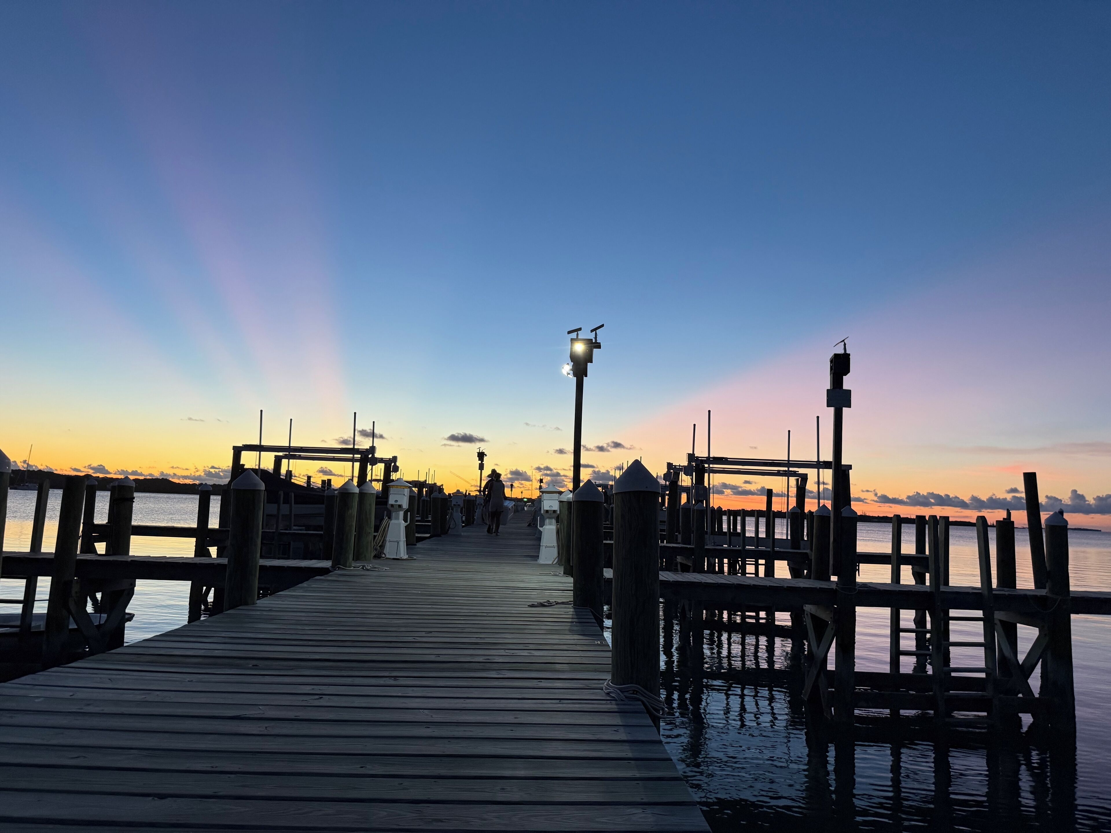 Ein hölzerner Steg, der sich in ruhiges Wasser bei Sonnenuntergang erstreckt.