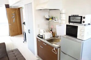 A compact kitchenette with a microwave, toaster, and sink.