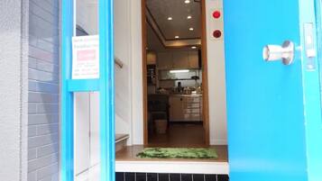 A hotel entrance with a blue door, a sign indicating 'Paradise Inn', and a glimpse of a kitchen area inside.
