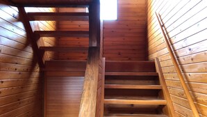 Eine Holztreppe in einer Hütte mit geneigter Decke und einem Oberlicht.