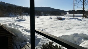 Eine verschneite Landschaft mit einer Holzhütte und freiem Blick auf die umliegenden Hügel.