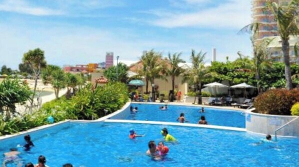Relax by the resort's expansive pool surrounded by lush greenery and palm trees.