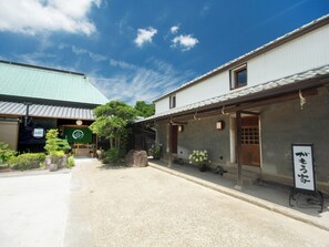 Ein traditionelles japanisches Gebäude mit einem Ziegeldach, einer Steintorii und einem Schild.
