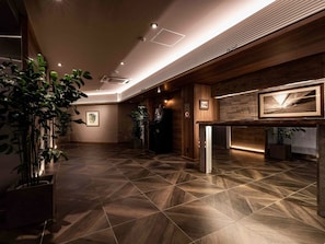 En modern entréhall med ett golv i geometriskt mönster, träpanel och en receptionsdisk med inramade konstverk.