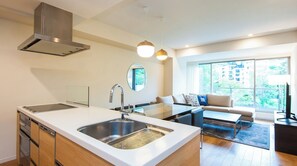Una cocina moderna con una isla grande, un comedor con mesa de vidrio y un sofá con vistas a la ciudad.