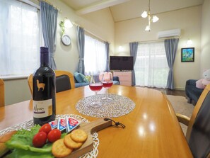 Un'area pranzo con un tavolo apparecchiato per due, con una bottiglia di vino Alpaca del Cile, due bicchieri di vino rosso, un piatto di pomodorini ciliegino e dei cracker.