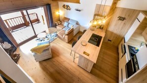 Un interior moderno con piso de madera, una isla central con pileta, un sofá y un comedor.
