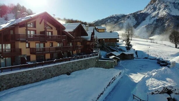 Un edificio de estilo chalet con varios balcones y una pared de piedra en un paisaje nevado.