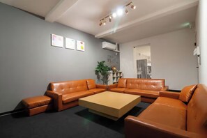 Un salon moderne avec un canapé d’angle, une table basse et une bibliothèque.
