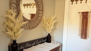 Une pièce comprenant une commode en bois, un miroir orné d’un cadre en macramé et une décoration murale en macramé.
