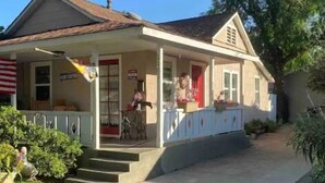 Une maison à deux étages avec un porche, des marches menant à la porte d’entrée et un petit jardin.