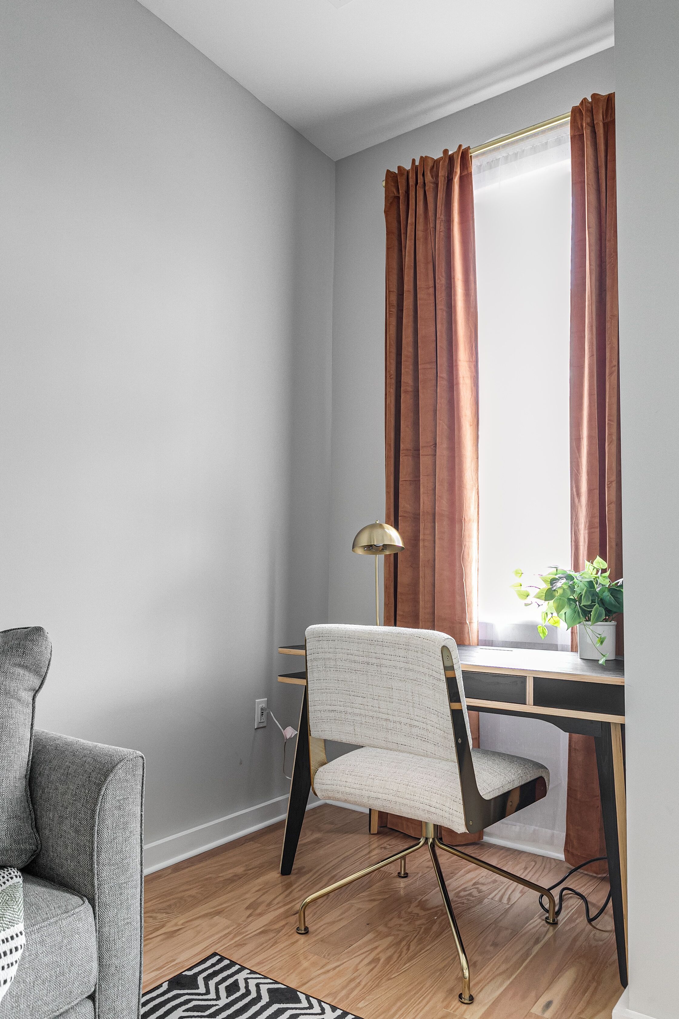 A modern office space with a desk, chair, lamp, and a potted plant.