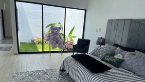 A bedroom with a large window, a bed with striped bedding, a dark armchair, and a patterned rug. - House Las Palmas (TICUMAN)