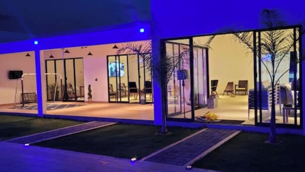 A modern building with large glass doors and windows, a flat roof, and a well-maintained lawn. - House Las Palmas (TICUMAN)