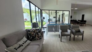 A spacious living room with a large window, a sofa, two armchairs, and a piano. - House Las Palmas (TICUMAN)