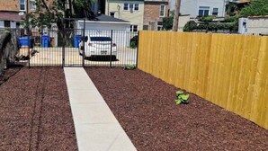A pathway leading to a gated area with a fence and a yellow fence on the right.