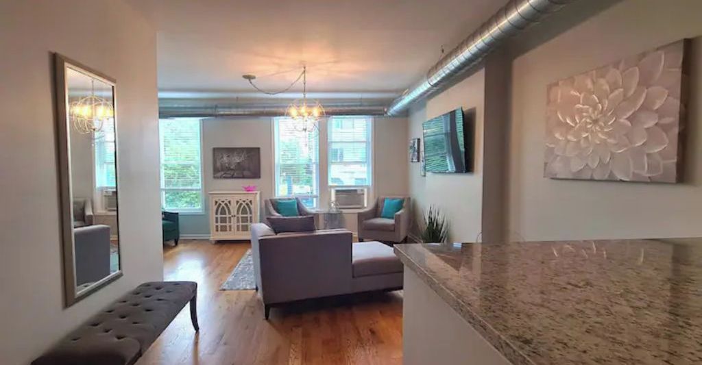 A modern living room with a sofa, a bench, and a large decorative wall piece.
