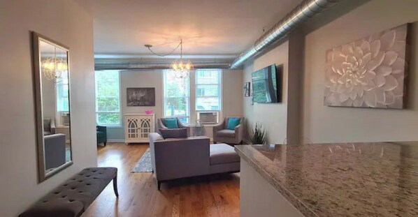 A modern living room with a sofa, a bench, and a large decorative wall piece.