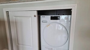 Eine kompakte Waschmaschine und ein Trockner, die unter einem Küchenschrank eingebaut sind.