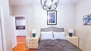 A bedroom with a bed, two bedside tables, a chandelier, and artwork on the walls. - Medical District Gem III (Chicago)