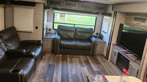 Ein gemütliches Wohnmobil-Interieur mit einer Ledersofa, einem Fernseher und einem kleinen Tisch.