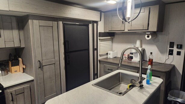 Eine moderne Küche mit Holzausstattung, einem Edelstahl-Spülbecken und einem eingebauten Toaster.