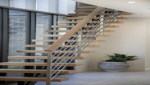 Un escalier moderne avec des marches en bois et des rampes en métal, menant à l’étage supérieur.