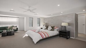 Une chambre à coucher moderne avec un grand lit, un ventilateur de plafond et une table de chevet avec une lampe.