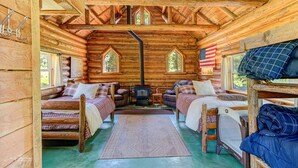 L’intérieur d’une cabane en rondins, avec deux lits, une cheminée et un drapeau américain.