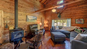 L’intérieur d’un chalet rustique, avec une cheminée, des meubles en cuir et une tête de cerf accrochée au mur.