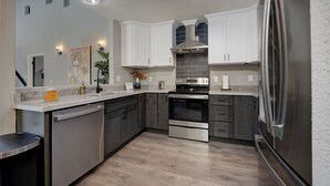 A modern kitchen with stainless steel appliances, white cabinetry, and a wooden floor. - Sacramento Retreat w/ Pool, Tub, & Backyard Golf Oasis (Sacramento)