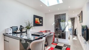 Una cocina moderna con una isla central, taburetes de bar y un comedor con alfombra estampada.
