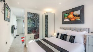 Un dormitorio moderno con una cama grande, una mesita de noche, un armario y un panel decorativo.