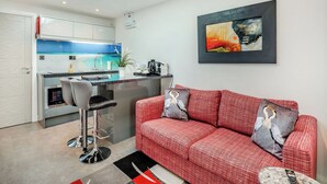 Una cocina moderna con tragaluz, un rincón comedor con sofá rojo y un cuadro en la pared.