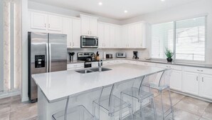 A modern kitchen with white cabinets, stainless steel appliances, and a central island with bar stools. - New Listing! Solara Resort, 8mi to Disney & 15mi to Universal - GRH488587 (Reunion)