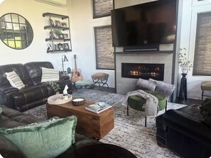 A living room with a fireplace, a TV, a guitar, and a couch.