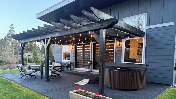 Un patio couvert aménagé avec du mobilier d’extérieur, un jacuzzi et des guirlandes lumineuses.