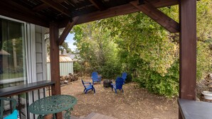 A covered patio area with a wooden deck, a table, and blue chairs. - Secluded in the City! New remodeled 2 bedroom near Berkeley Lake, pet friendly. (Denver)