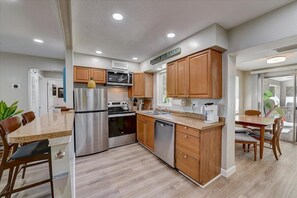 Enjoy cooking in this well-equipped kitchen with a central island, stainless steel appliances, and a dining area with a view.