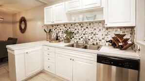 Una cocina moderna con armarios blancos, salpicadero azulejado y lavavajillas.