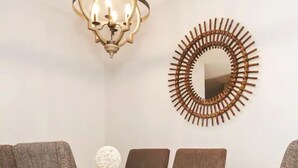 Un comedor con una araña, un espejo circular en la pared y un adorno redondo también en la pared.