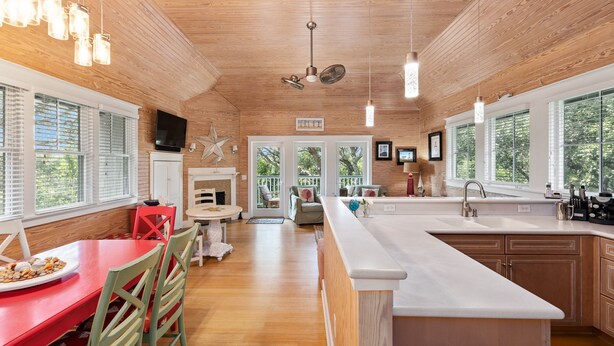 Una cocina moderna con armarios de madera, una isla grande y un comedor con sillas rojas.