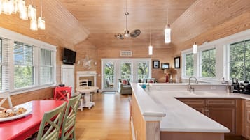 Une cuisine moderne avec des meubles en bois, un grand îlot central et un coin repas avec des chaises rouges.